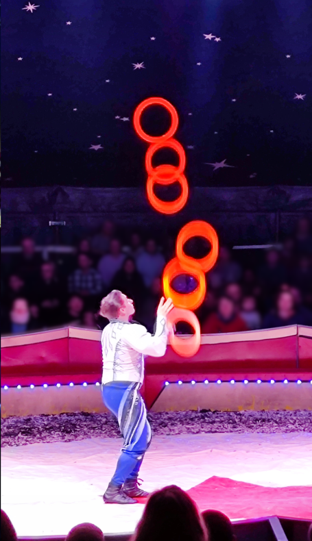 Ein Jongleur balanciert fünf Ringe während einer Zirkusvorstellung.